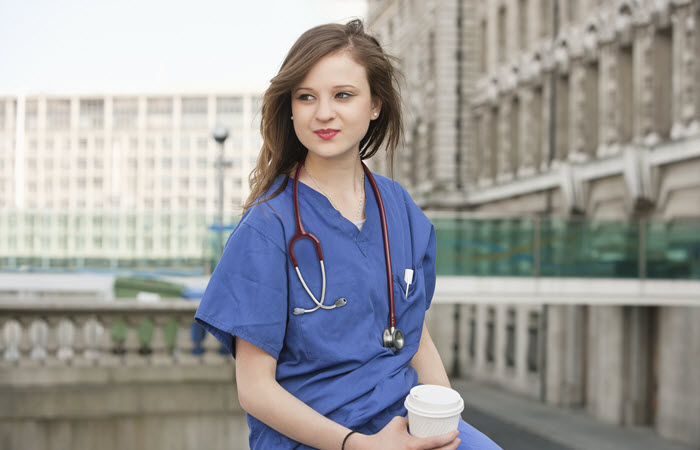 Female doctor in blue scrubs enjoying coffee